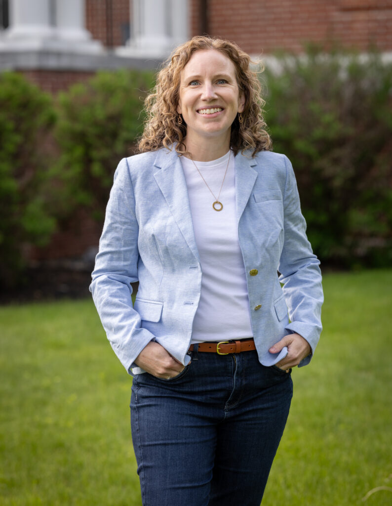 Leda Werrell, DNP, FNP-C, wearing blue jacket and smiling in front of brick building