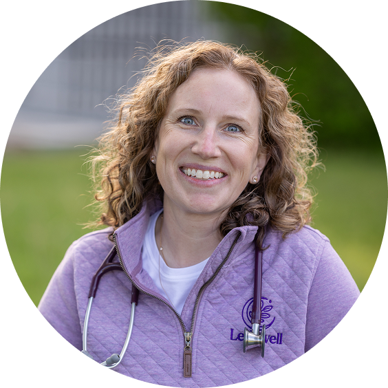 Leda Werrell, DNP, FNP-C, wearing purple pullover and stethoscope, sitting at picnic table